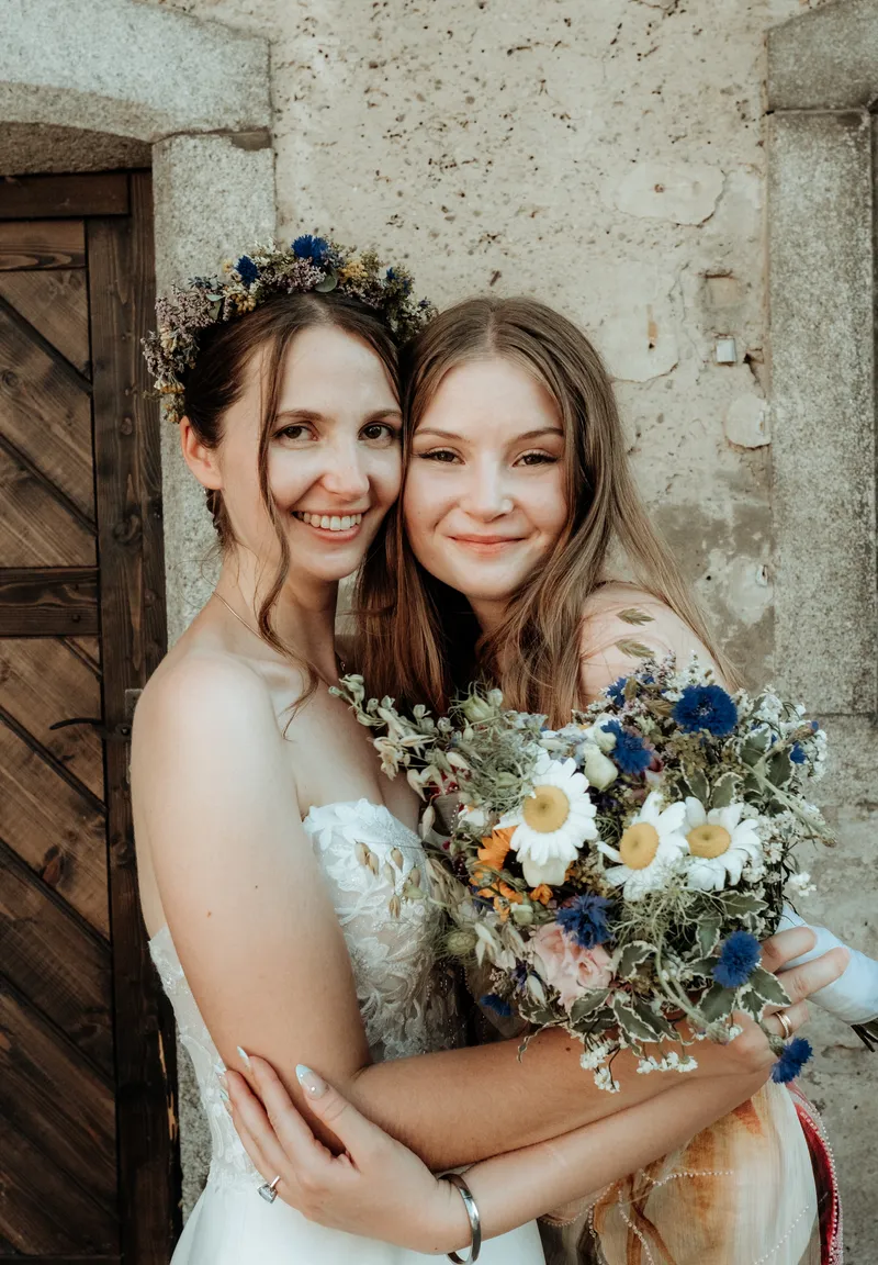 Zwei Frauen umarmen sich mit Blumenstrauß
